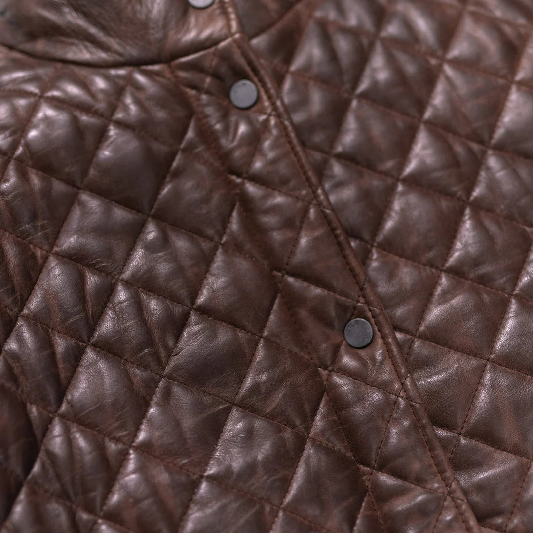 Close-up of a brown quilted leather jacket with diamond pattern and button details.