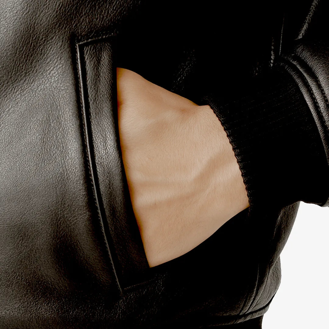 Close-up of a black leather jacket with a pocket showing skin underneath.