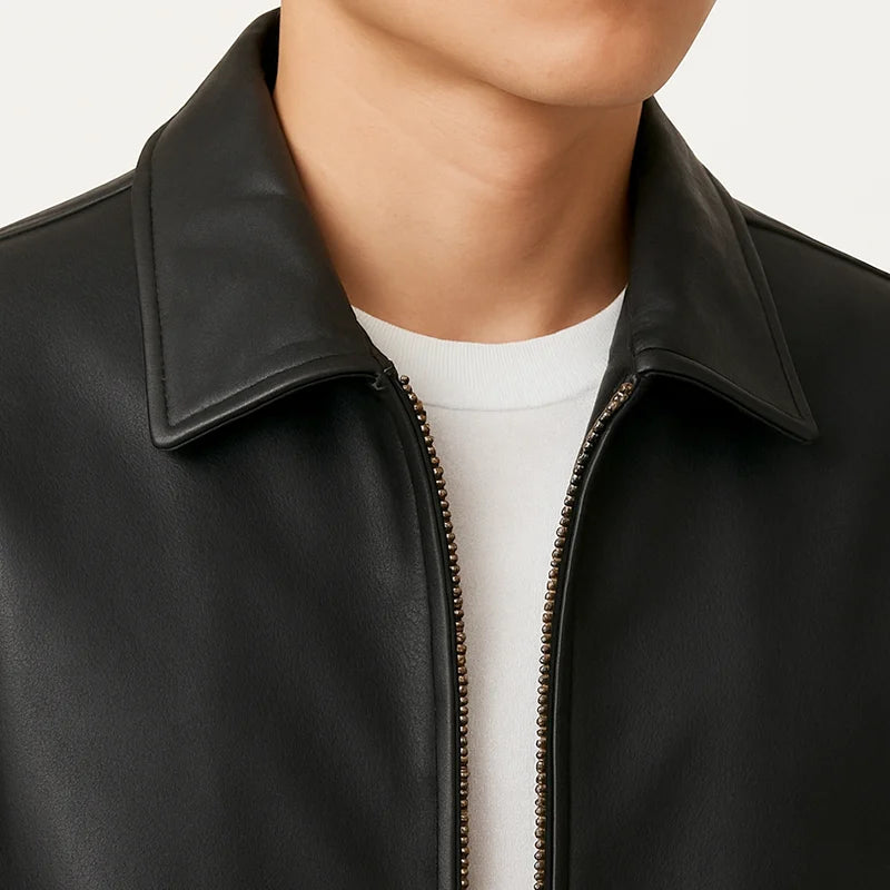 Close-up of a person wearing a black leather jacket with a white shirt underneath.