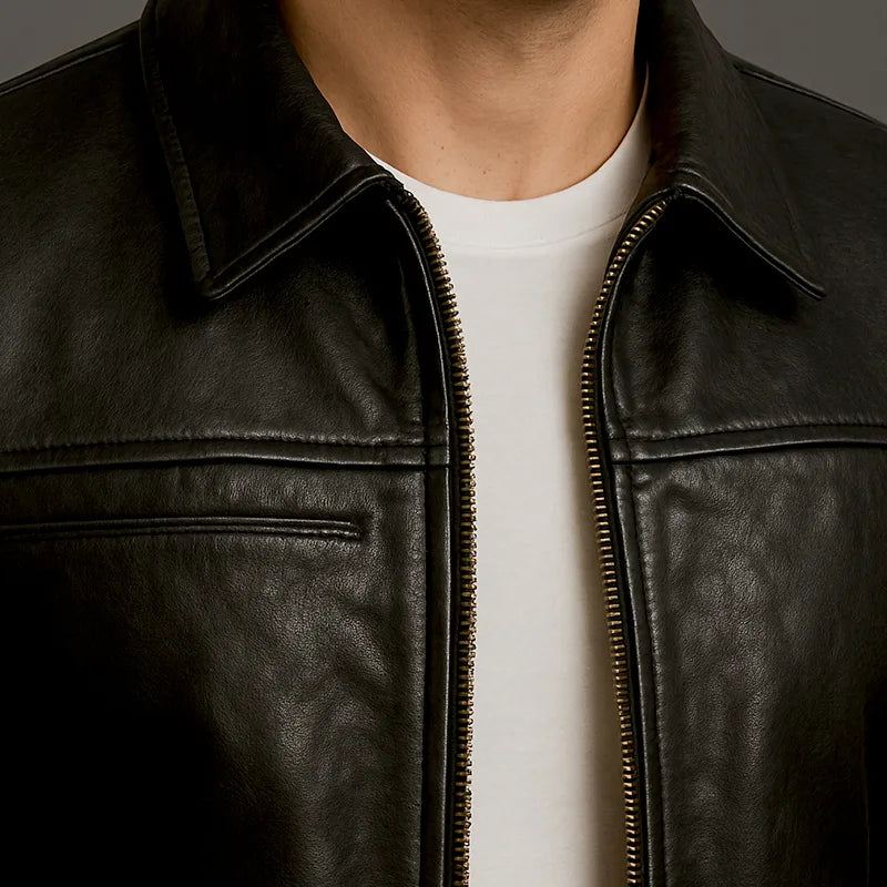 Black leather jacket worn by a person with a white shirt underneath, on a dark background