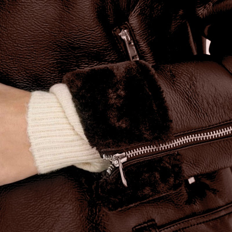 Close-up of a brown leather jacket with fur-lined cuffs and a hand wearing a white glove.