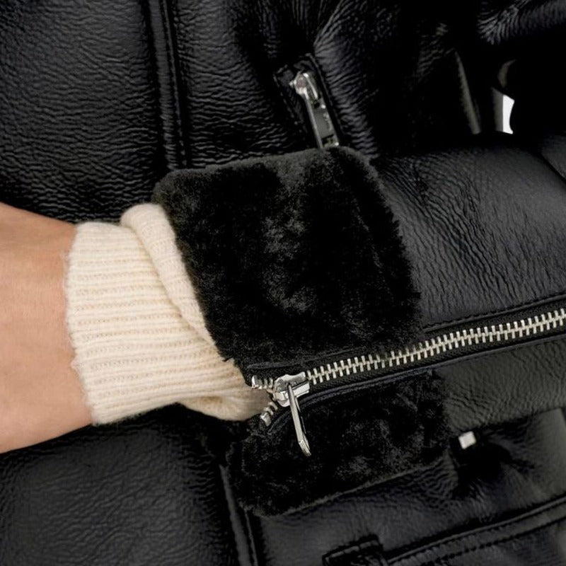 Close-up of a person wearing black gloves with fur cuffs and a black leather jacket.
