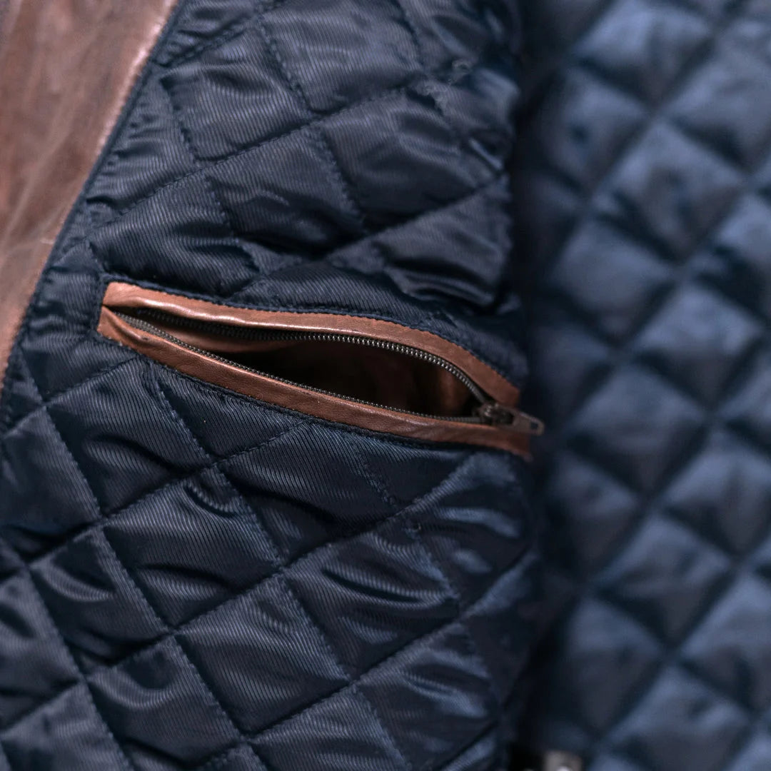 Close-up of a navy quilted jacket with a brown zipper pocket.