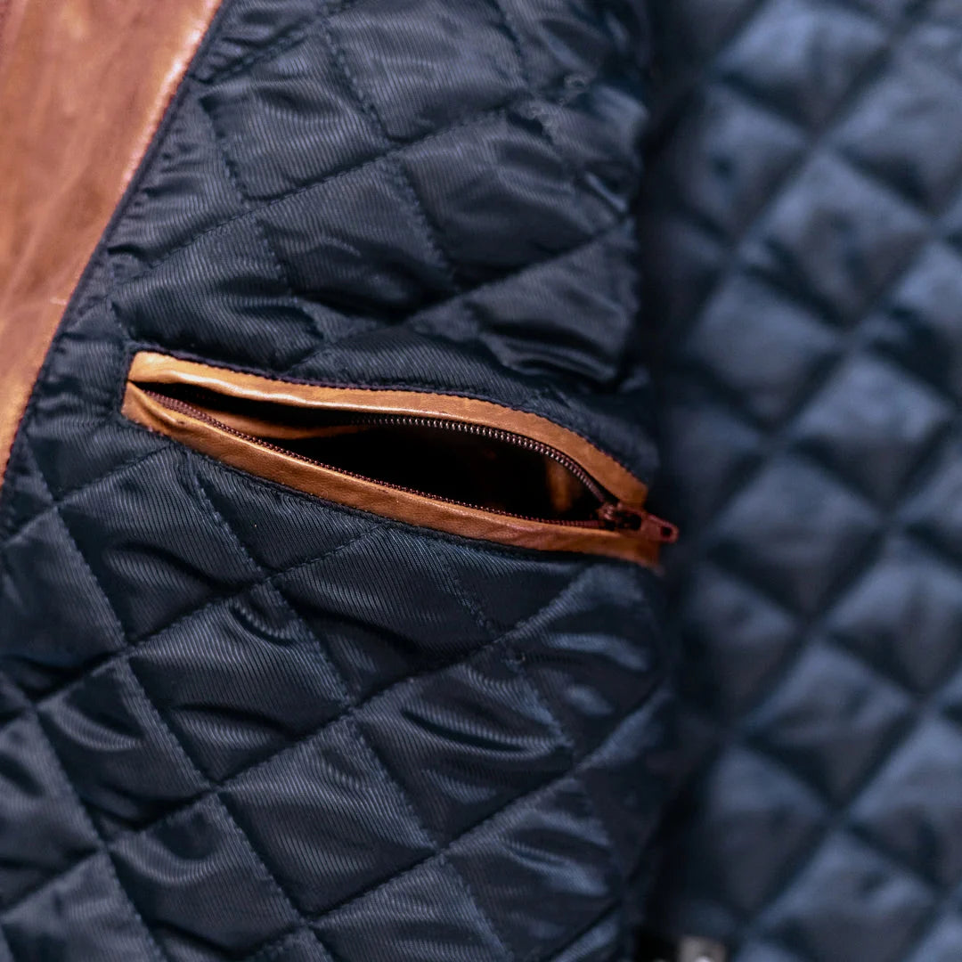 Close-up of a navy quilted jacket with a brown zipper pocket.