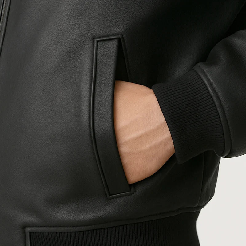 Close-up of a person wearing a black jacket with a hand in the pocket on a light gray background