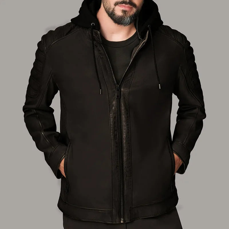 Man wearing a black jacket with leather accents on a gray background
