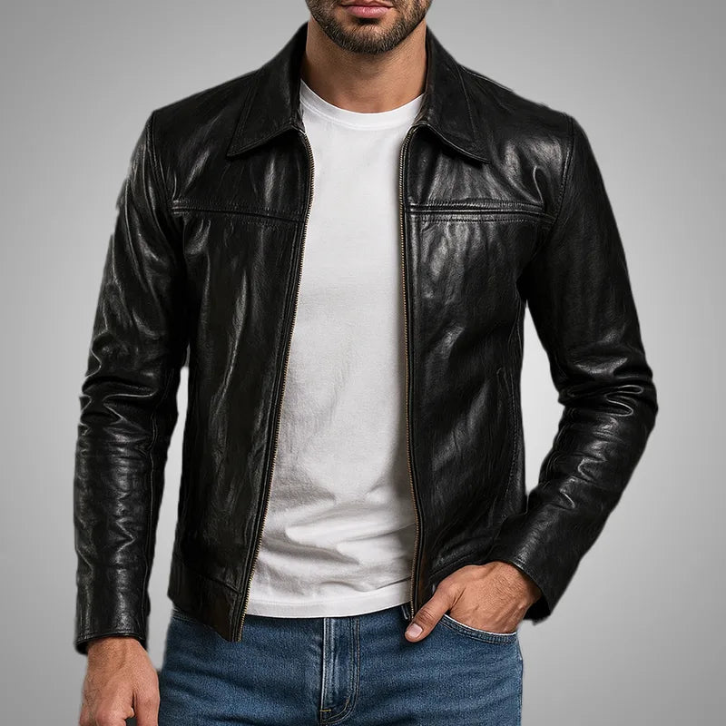 Man wearing a black leather jacket over a white shirt with a gray background