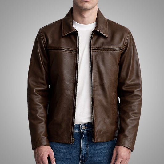 Man wearing a brown leather jacket over a white shirt and blue jeans on a gray background