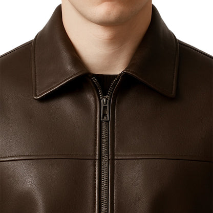 Close-up of a brown leather jacket with a zipper on a white background